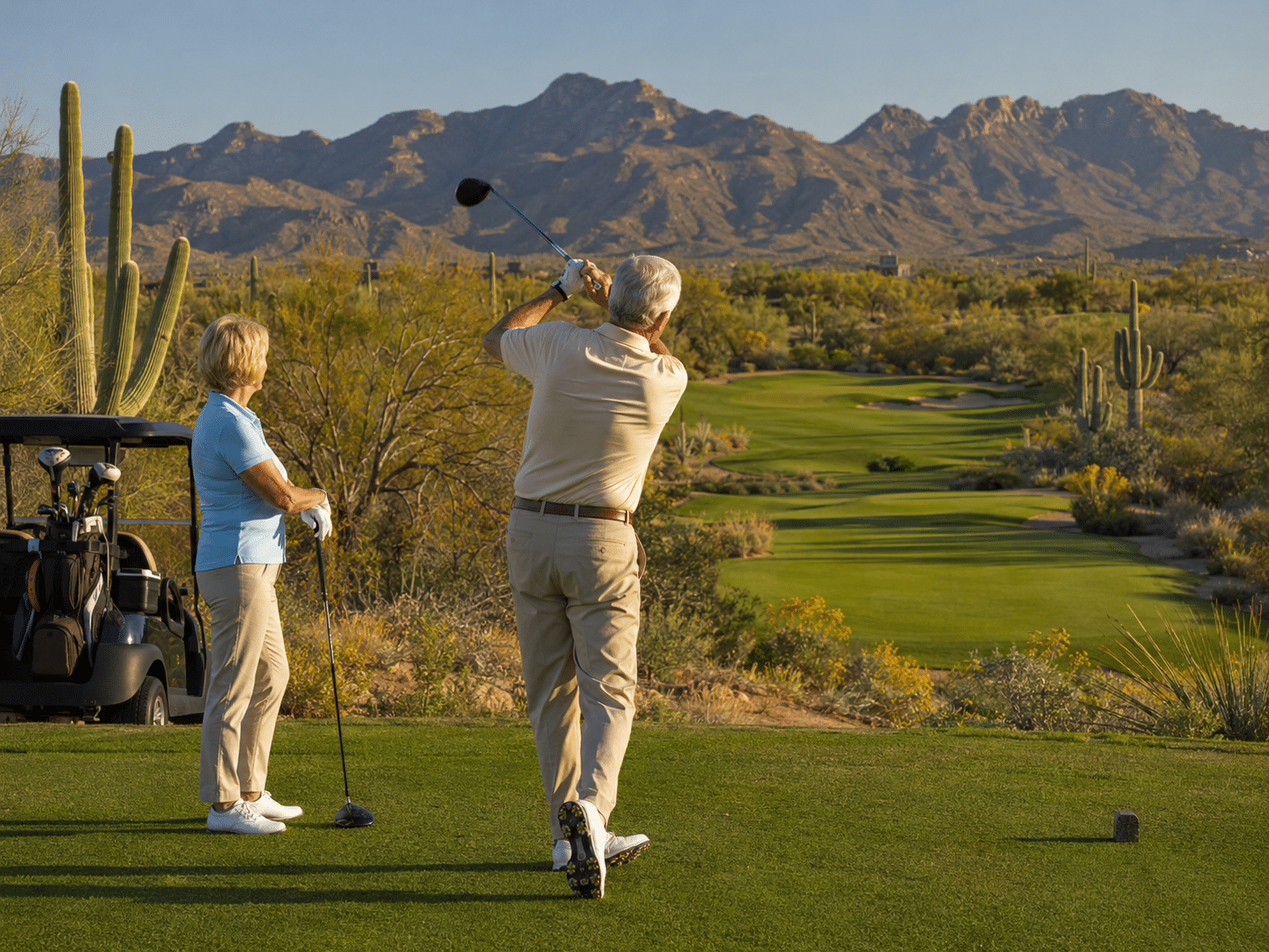 active-adult couple in their late 60s on the tee box of a par-four hole at the Verde River Golf and Social Club