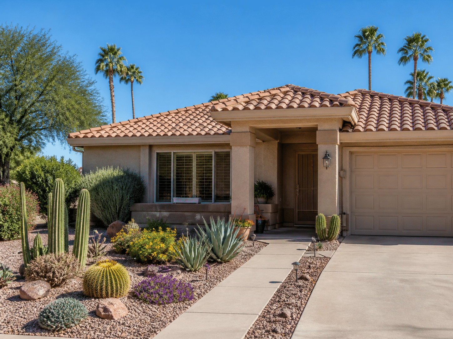 Exterior of a single-story Sun City West patio home with mature desert landscaping, a tile roof, and a covered front entry under bright morning light.