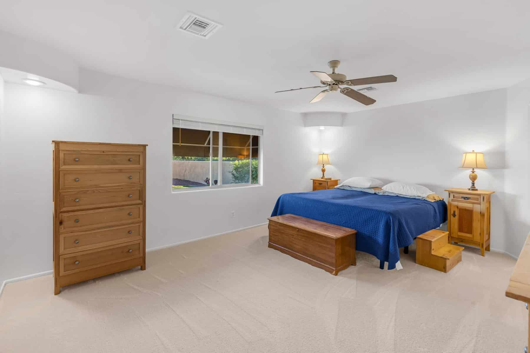 Bedroom with new carpet, ceiling fan and a window to the backyard