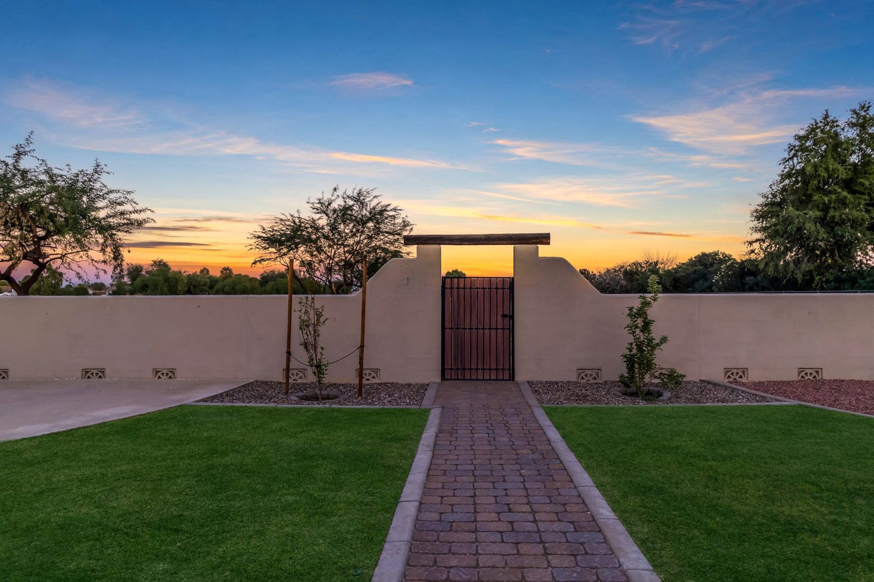 Paver walk leading to the gate in the back wall at sunset